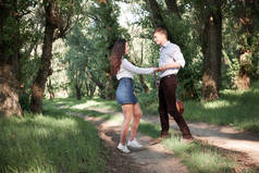 年轻的情侣漫步在森林里, 弹着吉他跳舞, 夏日的自然, 明媚的阳光, 阴影和绿叶, 浪漫的情怀