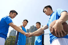 年轻的亚洲篮球运动员在玩游戏前把拳头拼在一起以示团结.