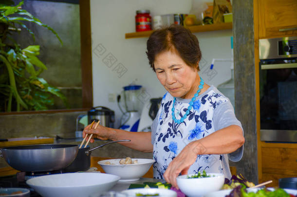资深快乐亚洲日本人的生活方式肖像退休了, 在家里做饭的女人独自一人整齐整洁地享受准备膳食和成熟的家庭厨师概念
