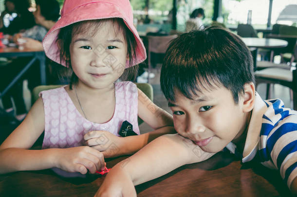 可爱的亚洲女孩<strong>微</strong>笑着与她的兄弟在咖啡馆完美的<strong>微</strong>笑。幸福的家庭花时间在一起, 爱和兄弟姐妹的结合。复古<strong>电影</strong>效果.