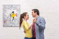 快乐的成人情侣跳舞在白色砖墙前面与抽象图片