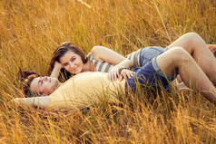 爱的情侣躺在秋季公园的花卉领域, 在温暖的阳光明媚的日子, 幸福和爱的概念