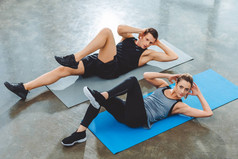 运动的年轻夫妇在健身房做腹肌运动