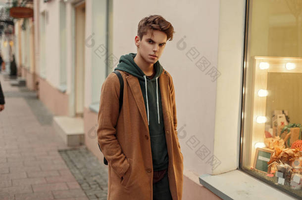年轻时尚的人在一个时髦的复古大衣在商店橱窗附近理发