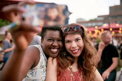 不同群体的两个女孩在夏季音乐节的人群拍照拍照