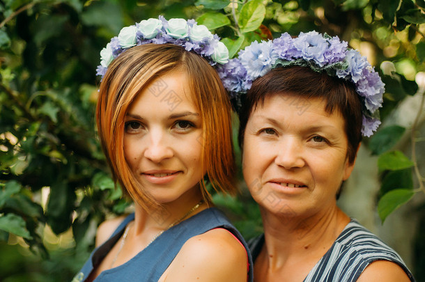 微笑的母亲和女儿的肖像在花圈中摆姿势 