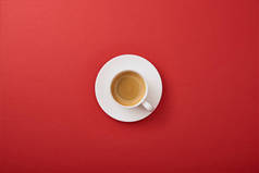 白色杯子的顶视图与咖啡在红色背景的碟子上