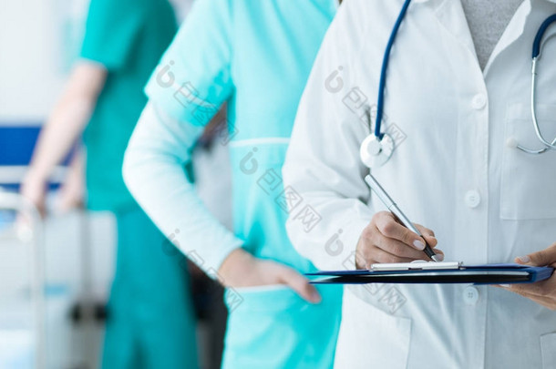 在医院工作的医务人员: 医生和护士检查<strong>病人</strong>的病历记录在剪贴板上, 医疗保健和医学考试的概念