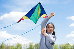 公园内抱风筝的微笑儿童的低角度观