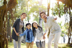 亚洲家庭与两个孩子有乐趣在公园里探索树林.