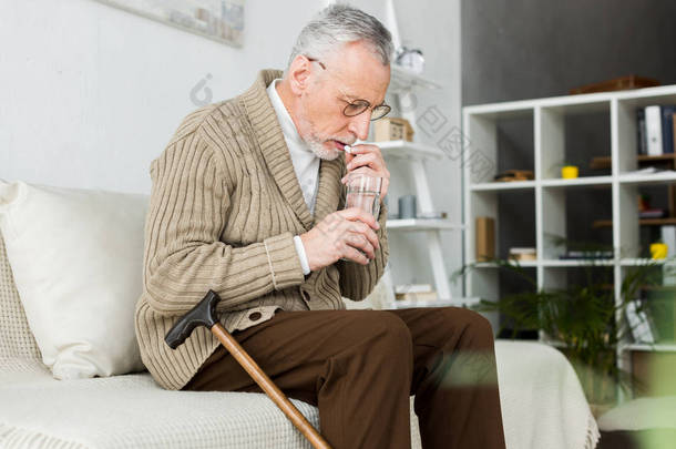 老人吃药, 而坐在沙发上附近走甘蔗 