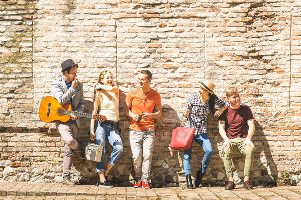 快乐兴奋的朋友群愉快的<strong>户外</strong>欢呼与吉他-青年人享受春天夏天时间一起在城市游览-青年友谊概念在温暖的下午颜色过滤器