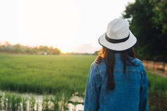 后面的年轻女子戴帽子。女孩享受美丽的自然与日落。旅游暑假假期与休闲理念.
