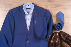 一套经典男装-蓝色西服、衬衫、棕色鞋子、腰带和木制背景领带.