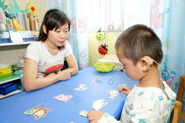 2017年5月27日，在中国南部的广西壮族自治区五州市，一名残疾男孩在老师的帮助下学习说话和倾听。