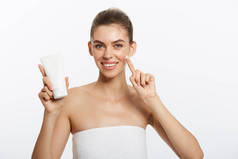 美容青春肌肤护理理念-美丽的白种女人脸上的肖像持有和呈现奶油管产品。美丽的水疗模特女孩.