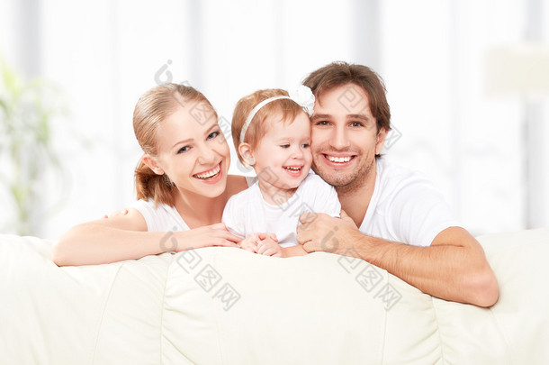 快乐家庭母亲、 父亲、 孩子宝贝女儿在家里在沙发上玩着笑着