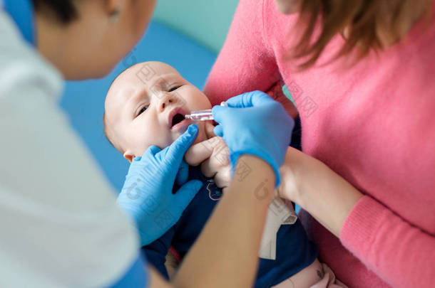 婴儿在母亲的手在医院。护士对婴幼儿轮状病毒感染进行口服疫苗接种。儿童保健与<strong>疾病预防</strong>