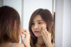 肖像 美丽的 亚洲 女孩 应用 粉泡 基础 镜子 在 卧室.年轻女子化妆的化妆品看镜子。清洁面部美容，健康和保健概念.