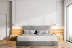 现代卧室的内部有白色的墙壁, 一层木地板, 一张双人床和两个床头台灯。阁楼窗口。3d 渲染模拟
