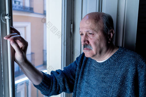 老老人看着整个窗口感到困惑和沮丧<strong>独自在家</strong>中老龄化退休鳏夫痴呆和阿尔茨海默症概念.