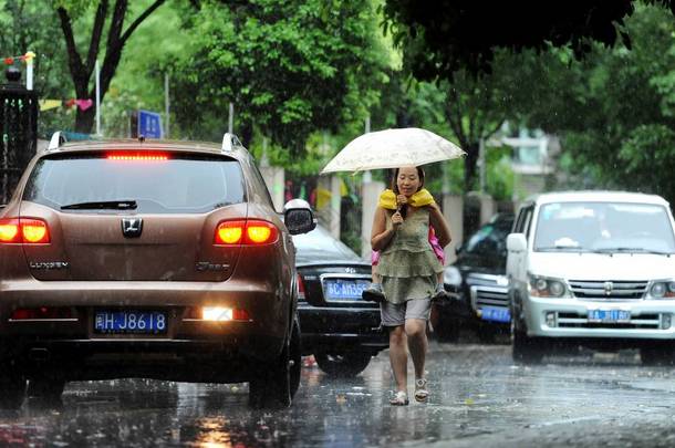 2013年9月13日，中国上海，一名妇女在一场<strong>大雨</strong>后，在被洪水淹没的街道上行走时抱着一个孩子。