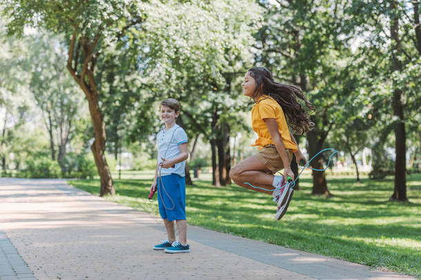 可爱的快乐的孩子玩跳跳绳在公园 