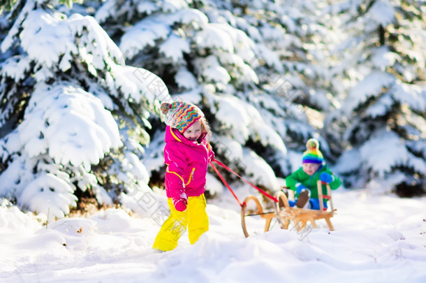 孩子们骑在白雪皑皑的冬季公园的雪橇