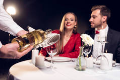 服务员倒酒, 而情侣在情人节的餐厅浪漫约会