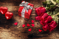 情人节婚礼的概念。玫瑰花束和红色的心在木桌上包裹的礼物