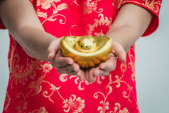 亚洲女子用旗袍捧着金子。春节.
