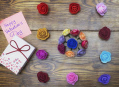 情人节的概念。带贴纸的礼品盒: 情人节快乐。木制背景下的花卉.