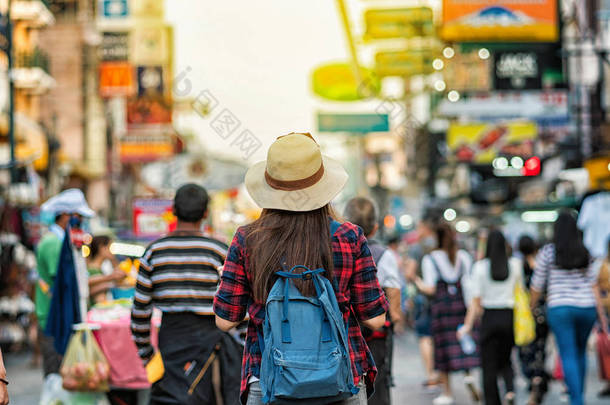 年轻的亚洲旅行妇女的背面步行和看在考山路步行街在晚上在泰国曼谷, 旅行者和旅游概念