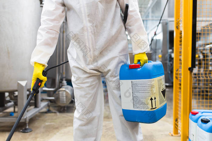 害虫防治工人手持喷雾器在生产或制造工厂喷