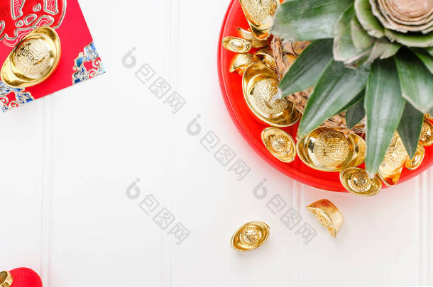 中国新年和战俘概念。顶部查看菠萝与组金锭在红托盘上的白色木桌上. 在锭意味着富裕.