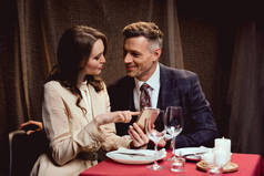 夫妇坐在桌子上, 并使用智能手机在浪漫的约会在餐厅