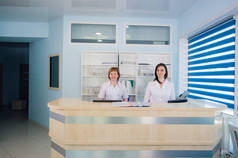 在医院接待处工作的两名面带微笑的护士