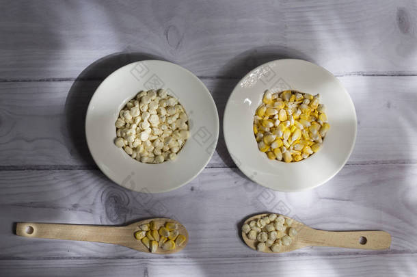 玉米玉米芯和黄色和白色的玉米谷物在白色木制背景的美丽的白色碗-伴随着丰富的沙拉玉米的玉米