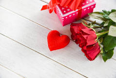 情人节礼品盒粉红色白色桌子背景/浪漫的红心情人节红玫瑰花和礼物盒丝带弓-爱的概念 