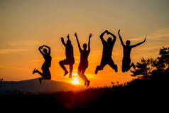 一群快乐的朋友们在惊人的日落中跳来跳去