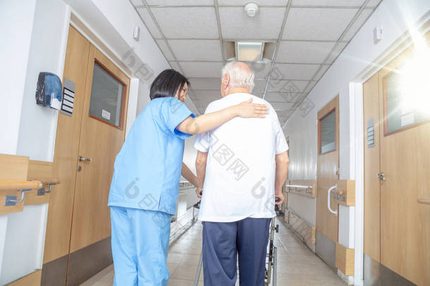 亚洲女医生用步行机安慰成熟的老年男子.男人和女人在医院的过道上开心的笑着。<strong>退休</strong>社区概念.
