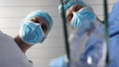 在医院里，医生和医生的助手使用不同的医疗工具进行治疗手术。两位医生都穿着长袍，戴着头饰和手套。概念：牙科医生.