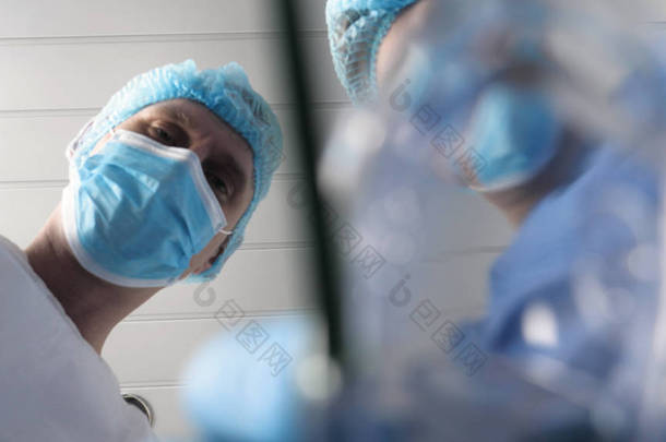 在医院里，医生和医生的助手使用不同的医疗工具进行治疗手术。两位医生都穿着长袍，戴着头饰和手套。概念：牙科医生.