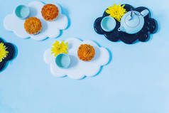 月饼，蓝茶壶，蓝色背景的黄菊花。中国中秋节食品.