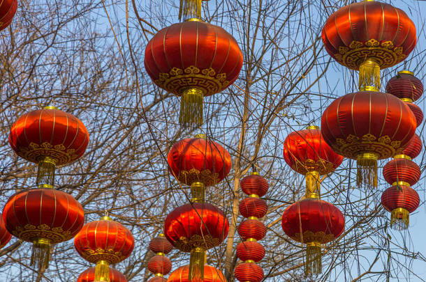 在中国北京，一条以蓝天为背景的街道上，几盏红色的中国灯笼