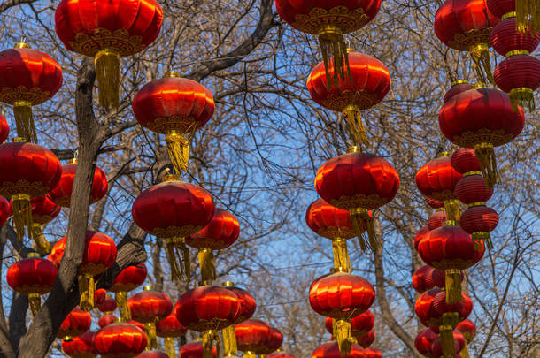在中国北京，一条以蓝天为背景的街道上，几盏红色的中国灯笼