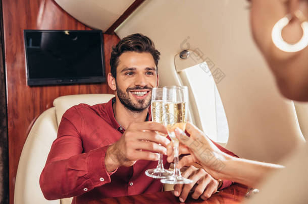 在私人飞机上，笑着的男友和女友与香槟酒杯叮当作响 
