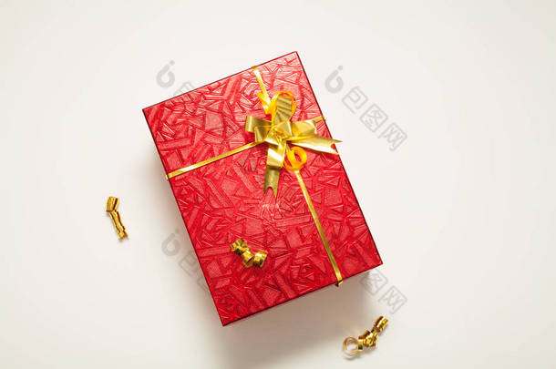 礼盒红色，闪烁着<strong>金色</strong>的蝴蝶结，装饰着<strong>金色</strong>的缎带和圣诞球，白色的背景上，有一个地方刻有题词。 新年或圣诞节的概念礼物.
