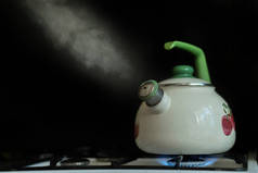 加热开水的水壶，水蒸气在黑暗的背景下从水壶里出来。