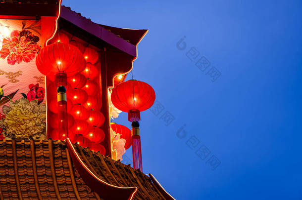 中国的红灯笼是农历新年的装饰品，挂在庙宇的屋顶上，背景是<strong>深蓝</strong>色的<strong>天空</strong>.